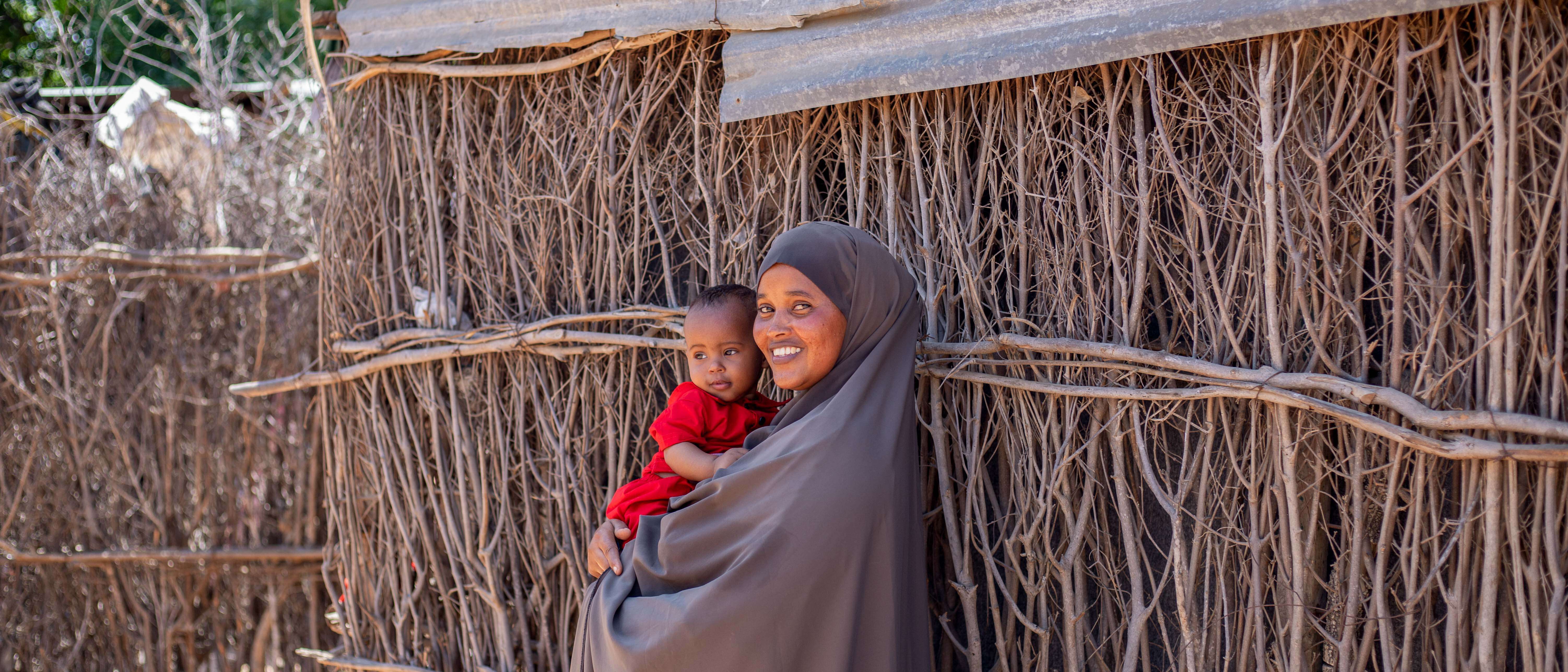 A mother holds her young child in her arms and the pair poses for a photo.