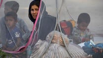 An Afghan mother sits in a tent with her young boys at a makeshift IDP camp. 